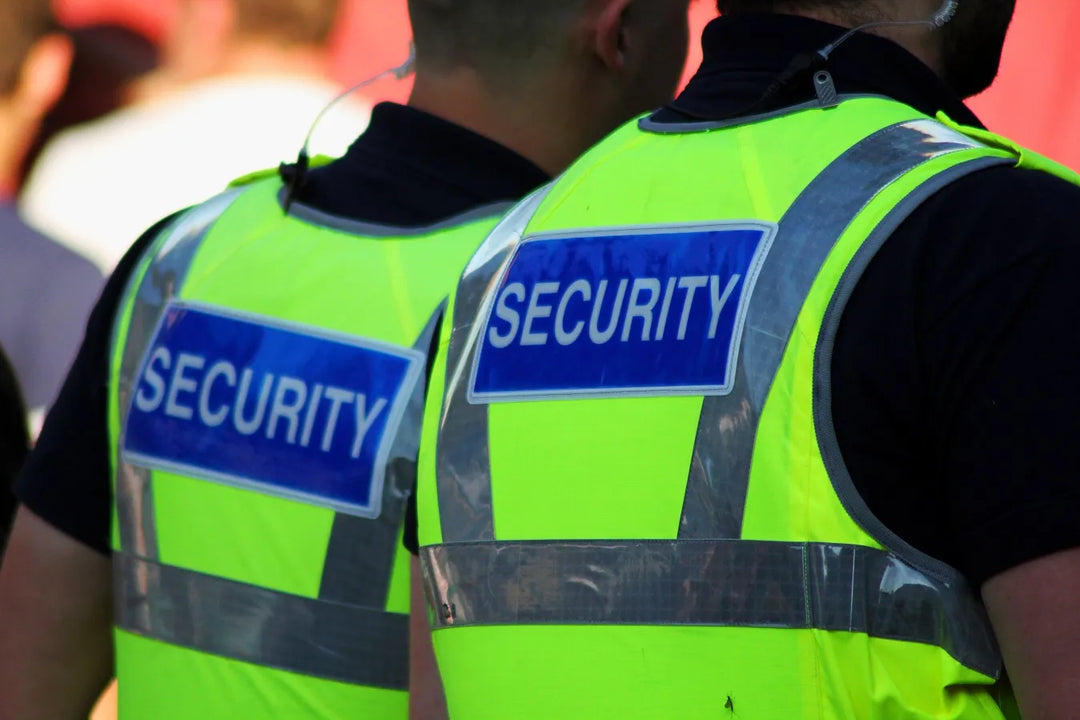 Dois seguranças com coletes verdes brilhantes com a inscrição 'SECURITY'.