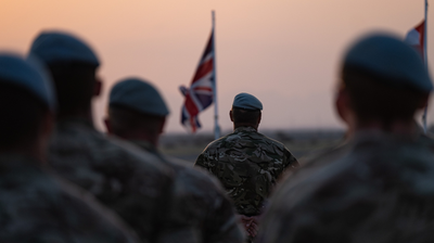 Global Excellence - Group of soldiers with British flags in the background during sunset.