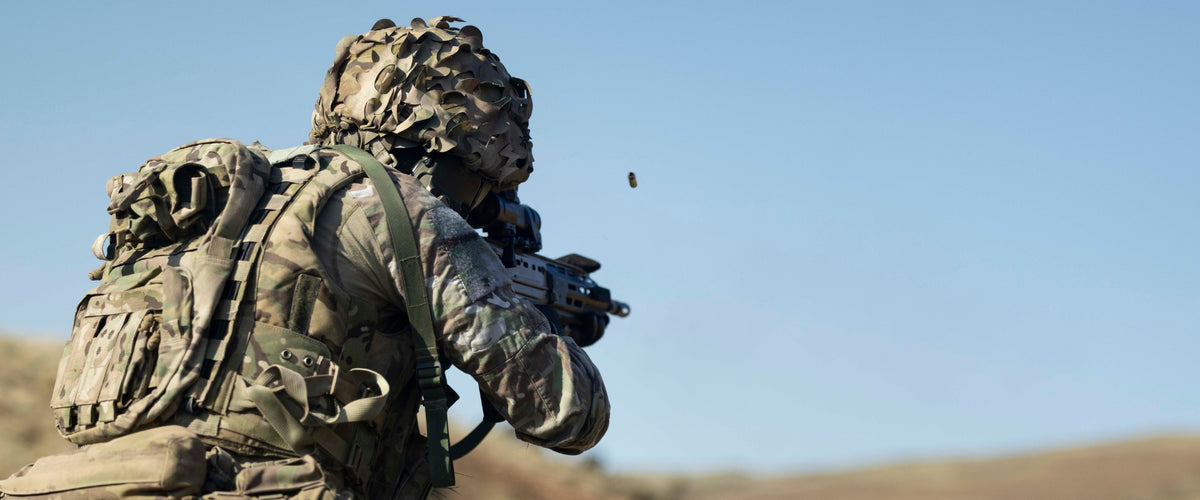Person in military gear with a rifle against a clear blue sky